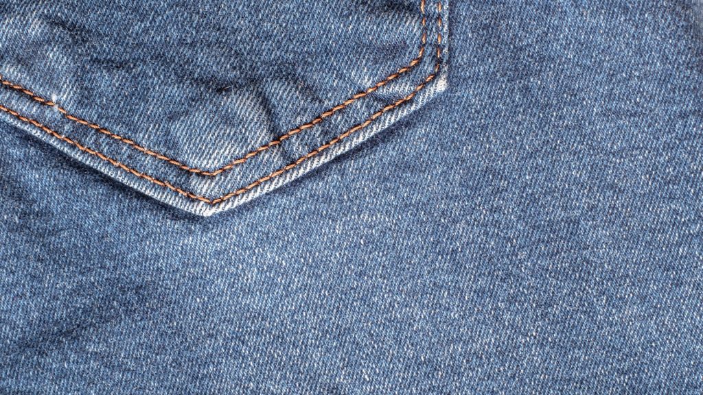 Surpiqûres orange doubles sur une poche de jean en denim bleu