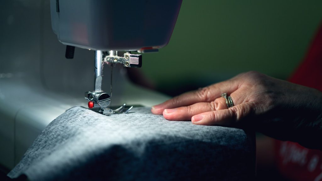 Main guidant lentement un tissu gris sous l'aiguille pour un essai de couture