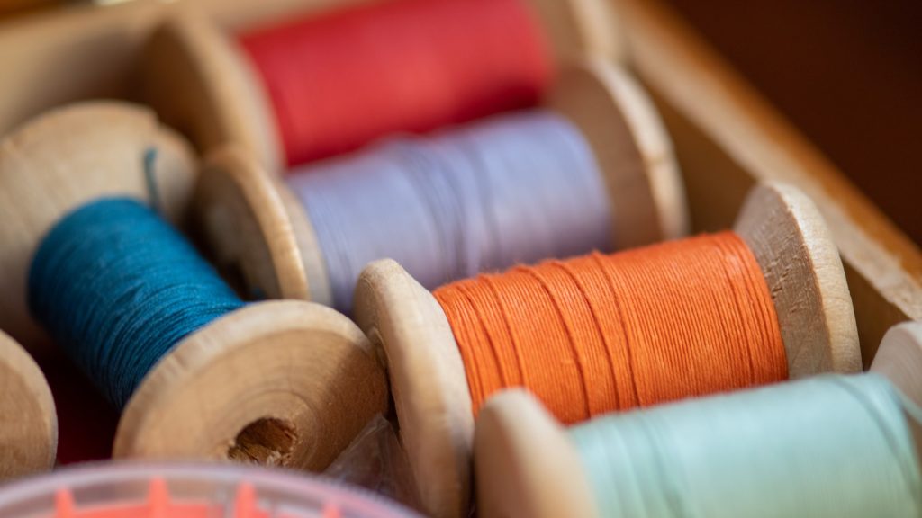 Bobines de fil en bois de différentes couleurs rangées dans une boîte