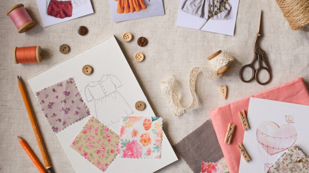 Plan de travail de couture avec échantillons de tissu, boutons, bobines et croquis